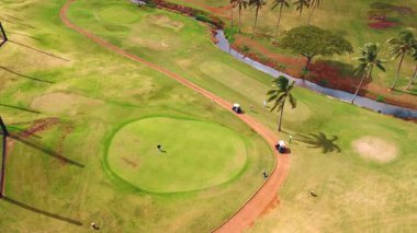 Dar bir yolu ve küçük bir nehri olan altın bir saha. Sahada çok az kişi oyun oynar. Hawaii, ABD. Üst görünüm.