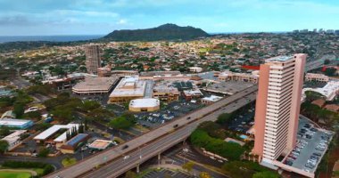 Düşük katlı binalarla dolu geniş bir şehir manzarası. Otobanların üzerinde araçlarla İHA uçuşu. Arkaplanda Elmas Kafası Krateri.