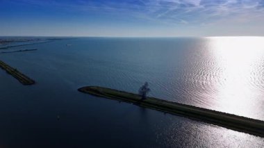 Hendeğin üzerinde oturan insan figürünün demir heykeline yaklaşıyoruz. Lelystad, Hollanda 'daki Markemeer Gölü' nün modern sanat eseri. Hava görünümü.