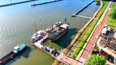 Rıhtımda duran yeniden inşa gemileri. İnsansız hava aracı denizden yükseliyor. Hollanda, Lelystad 'daki Batavialand Müzesi' ni gösteriyor..