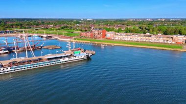 Hollanda, Lelystad 'daki Markermeer Gölü' nün kıyısındaki gemiler. Güneşli bir günde yeşil şehrin hava manzarası.