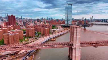 New York, ABD 'deki Brooklyn Köprüsü' nün desteğinden uzakta. Köprü ve nehir boyunca yol boyunca birden fazla araba hareket ediyor. Hava perspektifi.