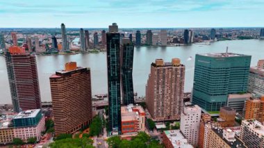 Modern şehrin manzarasındaki yeşil ağaçların üzerinden aşağı in. New York, ABD 'deki East River' ın arka planındaki binalara bakın..