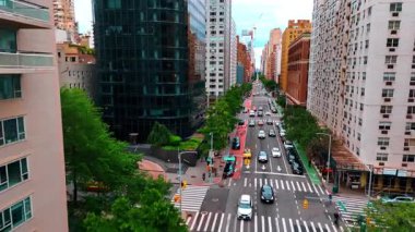 Yol boyunca büyüyen ağaçlarla güzel bir bulvar. Caddenin yukarısındaki İHA görüntülerinde birden fazla araba hareket ediyor. New York, ABD.