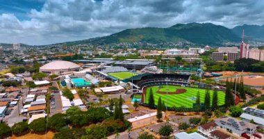 Honolulu, ABD 'deki Hawaii Üniversitesi' nin stadyumları yakınında yükseliyor. Arkaplanda dramatik bulutlar altında yeşil dağlar.