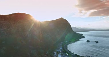 Dağın arkasından süzülen güneş manzarayı kamaştırır. Oahu, Hawaii, ABD kıyılarında insansız hava aracı uçuşu..