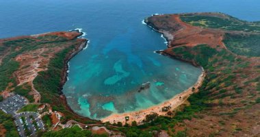 Pasifik Okyanusu 'nun at nalı şeklinde kayalık sahili. Hanauma Bay, Honolulu, Hawaii, ABD 'deki küçük kumsalın üstündeki İHA uçuşu..