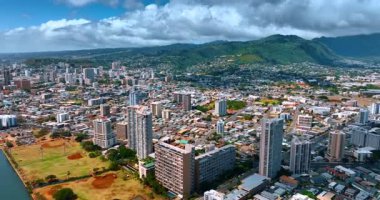 Sıcak güneşli bir günde Honolulu, Hawaii, ABD 'nin göz kamaştırıcı manzarası. Pofuduk bulutların altında yeşil dağlar. Hava görünümü.