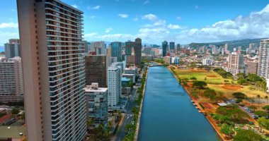 Arabalar Honolulu, Hawaii, ABD 'deki Ala Wai Kanalı boyunca otoyol boyunca ilerliyorlar. Kanal üzerinde yükselen İHA güzel güneşli şehir manzarasını gözler önüne seriyor.