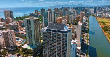 Çatıda güneş panelleri olan yüksek binaların üzerinde yükseliyor. Waikiki 'nin mimarisi yukarıdan görülüyor. Honolulu, Hawaii, ABD.
