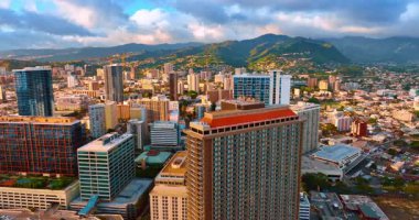 Batan güneşin ışığında Honolulu 'nun manzarası. Yamaçlarda yerleşim alanları olan güzel yeşil dağlar. Hava görünümü.