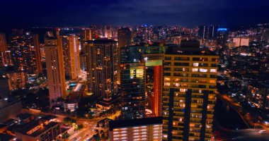 Yüksek binaların tepesinde uçarken pencerelerde aydınlatma açık. Canlı Honolulu, Hawaii, ABD Geceleri.