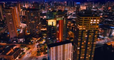 İnsansız hava aracı görüntülerinden Honolulu, Hawaii 'nin güzel aydınlanması. Geceleri ışıl ışıl parlayan manzaranın üzerinde yükseliyor.