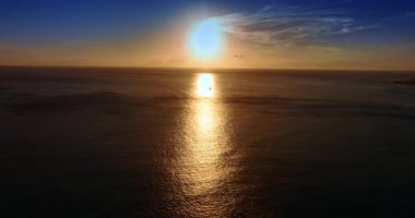 Küçük yelkenli engin sularda güneş ışığının yolundan geçer. Pasifik Okyanusu üzerinde muhteşem bir gün batımı. Hava görünümü.