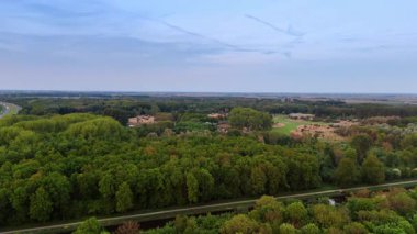 Hollanda 'nın kırsal kesimindeki yemyeşil ormanlar. İnsansız hava aracı görüntüsü dar bir nehre yaklaşıyor..
