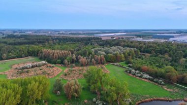 Hollanda 'nın kırsalında geniş tarım alanları, yeşil ormanlar ve çayırlar. Arka plandaki depolar. Hava görünümü.