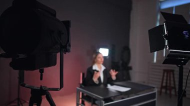 Arka planda oturan ve masada konuşan kadını aydınlatan çorapların görüntüsü. Program veya podcast 'in stüdyo görüntüleri.