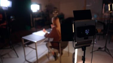 Stüdyoda oturan bir kadını aydınlatıyor. Modern fotoğraf stüdyosunun sahne arkasında..