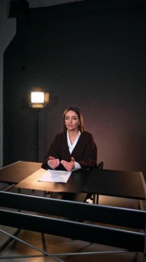 Programın sunucusu masada oturup kameraya el kol hareketi yapıyor. Blog konsepti. Stüdyo görüntüleri. Dikey video.