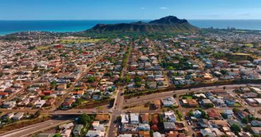 Volkanik kayanın dibine dağılmış güneşli şehir manzarası. Gök mavisi su manzarasının arka planındaki Elmas Kafa Krateri 'ne bak..