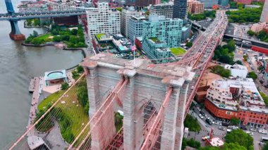 Çarpıcı Brooklyn Köprüsü 'nün desteğiyle rüzgarda dalgalanan Amerikan bayrağı. Köprü üzerindeki İHA uçuşu yollardaki trafiği gösteriyor. New York, ABD.