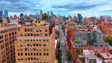 Modern metropolün işlek caddesi. Yüksek binaların tepesinde su tanklarıyla uçmak. New York havası bulutlu gökyüzünün altında.