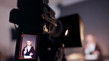 Kamera, kameraya konuşan bir kadın muhabiri gösteriyor. Kapatın. Blog ya da programın stüdyo görüntüleri. Bulanık arkaplan.