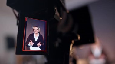 Bir bayanı konuşurken ve el kol hareketi yaparken gösteren modern bir kamera görüntüsü. Kapatın. Bulanık arkaplan.