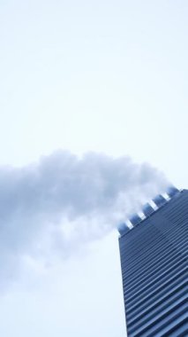 Modern ısıtma sobasından çıkan beyaz duman. Asansör ısıtma sistemi sigara içiyor. Dikey video