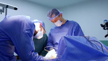 Kafkas erkek doktorlar beyin cerrahisinde işbirliği yapıyorlar. Sakallı cerrah, tıbbi alet kullanarak hastanın üzerine eğildi..