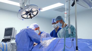 Ameliyathanede yuvarlak lambanın altında tıbbi ekip çalışıyor. Bir grup cerrah beyin cerrahisi yapıyor..