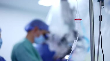Salin çözeltisi olan bir atık deposu. Ameliyathane ekipmanları kapatın. Bulanık arkaplanda mavi üniformalı doktor..