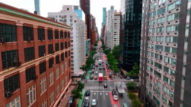 Çoklu şeritli yoldan geçen birden fazla araba ve otobüsü takip ediyorum. ABD 'nin New York caddesindeki renkli cephelerdeki İHA görüntüleri.
