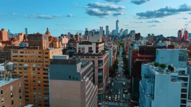 Meşhur Beşinci Cadde 'nin yukarısında bir sürü araba var. Binanın tepesinde güzel yeşil dinlenme yerleri olan bir binaya yaklaşıyoruz. Arkaplanda Manhattan gökdelenleri.