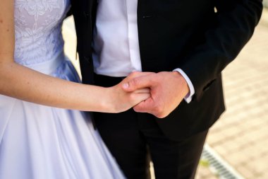 Çift düğünde el ele tutuşuyor. Gelin ve damat, açık hava ortamında düğün törenlerinde bir anı paylaşırken sıkıca el ele tutuşuyorlar..