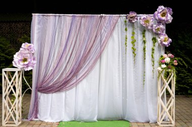 Açık hava etkinliği için çiçek arkaplanı. Geniş çiçekler ve örtülü kumaşla dekore edilmiş güzel bir arka plan. Açık hava kutlaması için mükemmel..