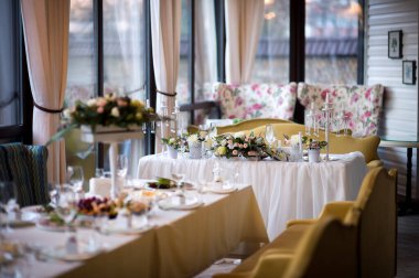 Özel bir etkinlik için şık bir yemek düzeni. Çiçekler ve mumlarla güzel düzenlenmiş bir masa. Sıcak, aydınlık bir mekanda kutlama için mükemmel..