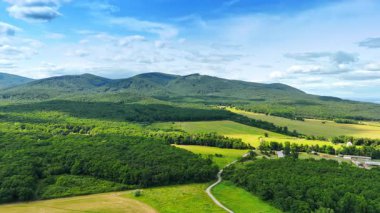 Avrupa 'daki yeşil tepeler. Güneşli bir günde, açık mavi gökyüzü altında, Avrupa 'daki yeşil tepelerin ve tarlaların geniş bir görüntüsü doğanın güzelliğini gözler önüne seriyor..