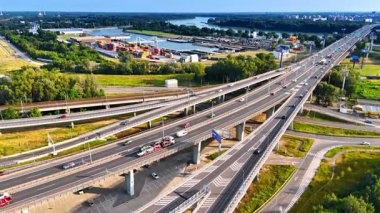 Avrupa otobanındaki arabalar. Avrupa 'da gün ışığında nehir ve sanayi bölgesi yakınlarındaki yoğun bir otoyol boyunca araçlar seyahat eder..