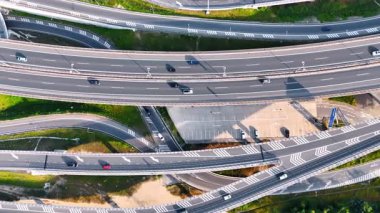 Avrupa 'nın yollarında trafik ilerliyor. Çok sayıda araç, berrak bir gökyüzünün altındaki hareketli Avrupa manzarasında karmaşık otoyollarda ve rampalarda gezinir..