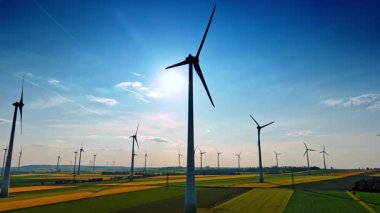 Rüzgar türbinleri temiz enerji üretir. Rüzgâr türbinleri, parlak mavi gökyüzünün altında zarif bir şekilde dönerek yenilenebilir enerji çabaları sergiliyor..