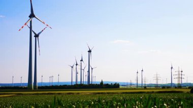 Rüzgar türbinleriyle güneşli bir gün. Açık mavi gökyüzünün altında birden fazla rüzgar türbini barındıran kırsal bir alanda rüzgardan elde edilen yenilenebilir enerji..