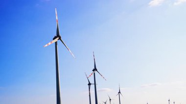 Parlak gökyüzünde türbinler. Rüzgar türbinleri temiz bir gökyüzünde dönüyor, temiz elektrik üretimi için rüzgar enerjisinden faydalanıyor..