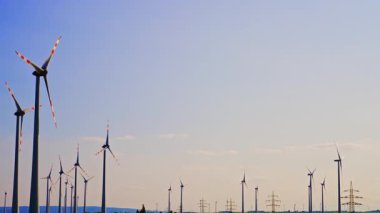 Güneş batan rüzgar türbinleri enerji üretiyor. Rüzgâr türbinleri, berrak bir gökyüzüne karşı dimdik durur. Gün batımında, huzurlu bir manzaranın yanında rüzgâr enerjisinden yararlanırlar..