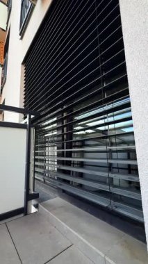 Jaluzili lüks modern bir bina. Çağdaş bir binada yatay siyah jaluzili büyük pencerelerden oluşan bir duvar, mahremiyet ve tarzın geliştirilmesi yer alıyor..