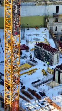 Vinçli ve işçili inşaat alanı. İşçiler, gün boyunca makineler ve inşaat malzemeleriyle çevrili bir alanda inşaat faaliyetlerinde bulunuyorlar..