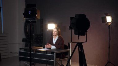 Kameranın önünde oturan ve konuşan bir kadının stüdyo görüntüleri. Bir günlük veya program için video içeriği oluşturma.