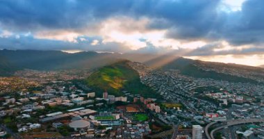 Batan güneş demetleri, Honolulu, Hawaii, ABD 'de gökyüzünü kaplayan devasa bulutların içinden geçer. Verdant Dağı ışık ışınıyla aydınlatılır. Hava görünümü.