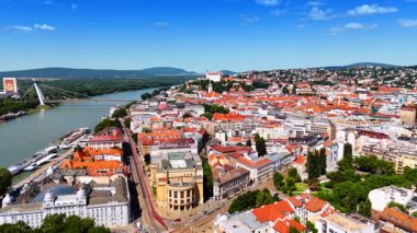 Bratislava ufuk çizgisi manzarası. Hava perspektifi Bratislava 'nın büyüleyici çatılarını, nehir kenarlarını ve açık mavi gökyüzünün altındaki yeşil tepeleri gösteriyor..