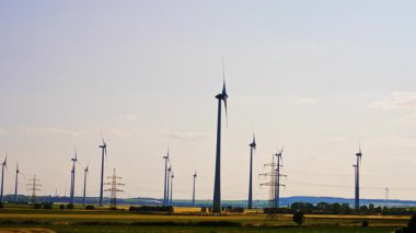 Türbinler yeşil enerji üretiyor. Rüzgâr türbinleri, açık bir günde kırsal alanda rüzgâr enerjisi yakalıyor ve sürdürülebilirlik gösteriyor..